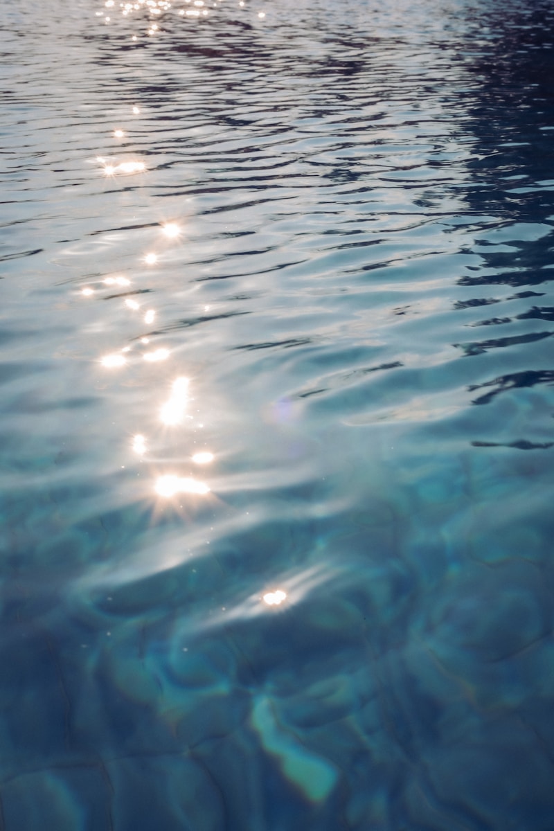 the sun shines brightly on the water of a swimming pool